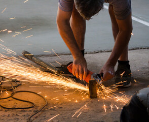 Man using grinder machine and throwing sparks to cut metal.