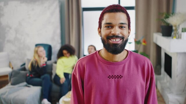 Portrait of an attractive African American guy on the background of a student party indoor. African american man posing against the background of a home meeting of friends