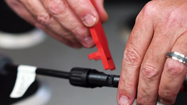 This High Definition at 23.976 fps footage shows the hands of a technician disconnecting a solar panel MC4 cable using the proper tool.