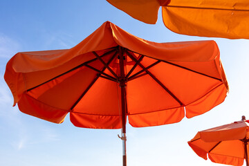 Vivid orange umbrella beach with bright blue sky in summer.