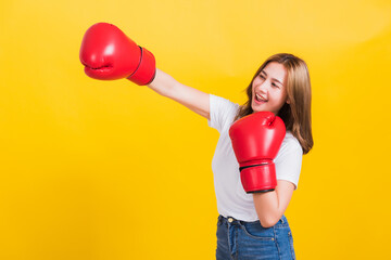 Portrait Asian Thai beautiful young woman standing smile wearing red boxing gloves and punch to...