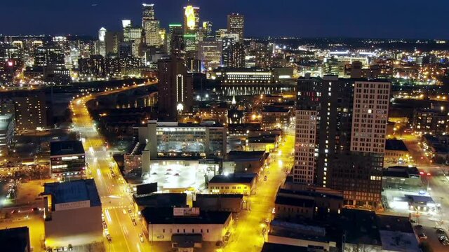 Aerial time lapse shot of illuminated cityscape with canal at dusk, drone flying forward over buildings against sky at night - Minneapolis, Minnesota
