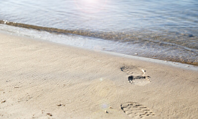 subtle image of footprints wearing shoes walking towards the water and not returning. Concept of death, suicide, murder mystery and drowning.