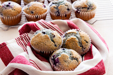 Fresh homemade blueberry muffins fresh out of the oven; golden blueberry muffins placed on a tea towel and cooling racks