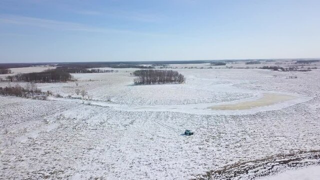 View from above. Inspector raid on a winter reserve in Russia on a swamp vehicle. A jeep on large wheels drives through a snow-covered field.