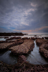 Amazing seascape for background. Beach with rocks and stones. Low tide. Motion water. Cloudy sky. Slow shutter speed. Soft focus. Mengening beach, Bali