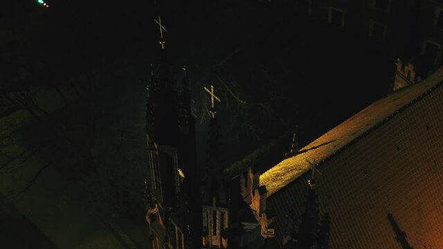 Old church with tall spires and crosses on top at night. Aerial high angle.