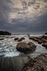 Beautiful seascape for background. Beach with rocks and stones. Low tide. Motion water. Cloudy sky. Slow shutter speed. Soft focus. Copy space. Vertical layout. Mengening beach, Bali