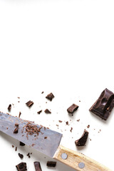 Finely chopped dark chocolate bar and old knife with wooden handle. Top view, flat lay.
