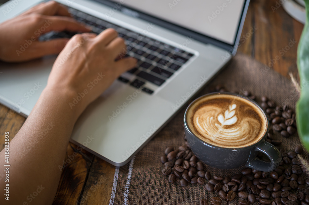 Wall mural woman working with laptop computer with latte art coffee cup and coffee beans on wood table, flat design