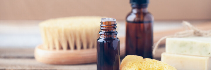 Natural organic herbal essential oil in apothecary bottles. Gentle skin care, aromatherapy, atmosphere of relaxation, anti-stress. Sponge, brush, handmade soap, wooden background. Copy space, banner