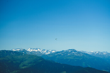 Fototapeta na wymiar ein Paraglider allein vor dem weiten Himmel über den Bergspitzen des Tirol und der Tauern in Österreich