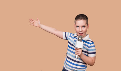 Young boy is recording his song in the studio. Singing child holds microphone in his hands on the same level with his opened mouth. Childhood lifestyle concept. Mock up copy space. Portrait handsome