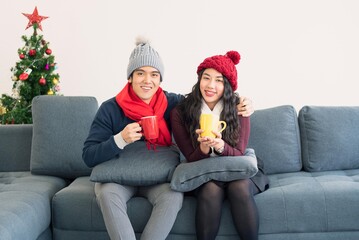 Asian man and woman couple family in casual outfit holiday winter theme drinking hot beverage coffee or tea with happy and romantic in modern living room