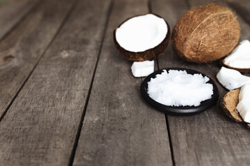 Fototapeta na wymiar Broken coconuts on gray wooden background. White fresh pulp on black plate
