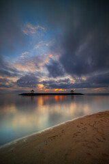 Sunrise seascape. Traditional gazebos on an artificial island in the ocean. Water reflection. Calm water surface. Soft focus. Vertical layout. Sanur sandy beach, Bali