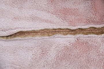 Fototapeta na wymiar Beige brown texture of fur fabric on clothes in the seam