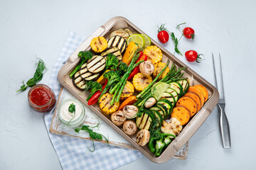 Grilled assorted vegetables in beige tray on light grey background.