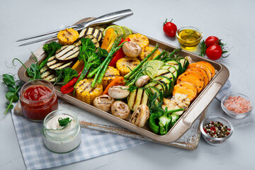 Grilled assorted vegetables in beige tray on light grey background.