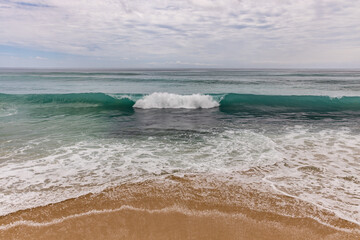 Seascape background. Sandy beach, milky foam waves, blue ocean. Scenic waterscape. Horizon line. Cloudy sky. Nature and environment concept. Daylight. Copy space. Dreamland beach, Bali