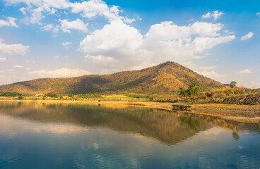 Fantastic blue sky, white clouds and mountains are reflected in the deep, still blue waters of a massive lake,Thailand. Beauty of nature concept background.
