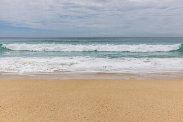 Fototapeta na wymiar Seascape background. Sandy beach, milky foam waves, blue ocean. Scenic waterscape. Horizon line. Cloudy sky. Nature and environment concept. Daylight. Copy space. Dreamland beach, Bali