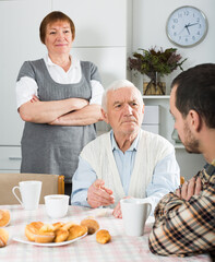 Mature father and mother quarrelling with their son at home