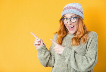 Surprised young woman while standing and pointing to blank space - copy space. Girl with happy laugh, half length body, isolated on white background