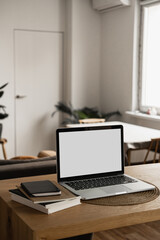Laptop with blank copy space screen on table with notebooks on wooden table. Minimalist home office workspace. Mockup template.