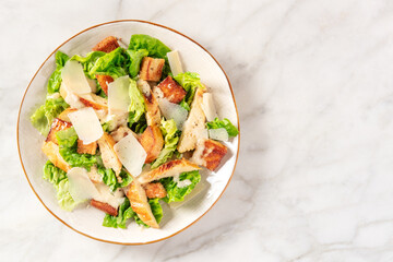Caesar salad with grilled chicken, romaine and cheese, shot from above with a place for text