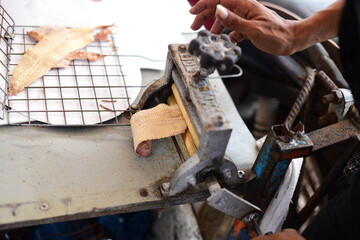 
A dried fish merchant grinds dried squid with hand-cranked uniforms on a cart on the beach of Jomtien, Pattaya, Thailand.