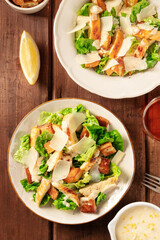 Caesar salad a dark rustic wooden table, with lemon and sauce