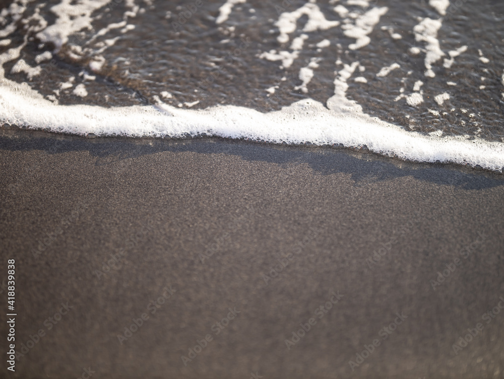 Wall mural Wave close up on black sand beach. Waterscape background. Selected art focus. Black sand beach with white milky foam waves. Nature and environment concept. Black and white contrast.