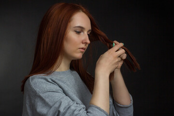 Obraz premium Red-haired young girl on black background in a gray T-shirt