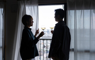 窓辺でワインを飲む日本人ミドル夫婦