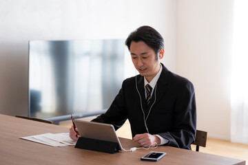 イヤホンをつけてタブレットPCを見る日本人ビジネスマン © arc image gallery