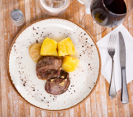 Fried pork with potatoes on a ceramic plate cooked in a restaurant