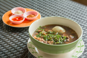 Vegan food concept. Hot Chinese roll noodle brown soup with boiled egg, tofu and mushroom in white bowl in restaurant.