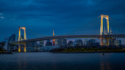 Fototapeta na wymiar Rainbow bridge with night illumination and Tokyo cityscape. Tokyo night skyline