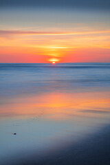 Naklejka premium Sunset and beach. Seascape background. Bright sunlight. Sun at horizon line. Scenic view. Colorful sky. Sunlight reflection in water. Magnificent scenery. Copy space. Bali