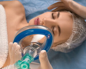 Close-up - the doctor gives anesthesia to the patient before surgery or beauty procedure. Focus on the mask.