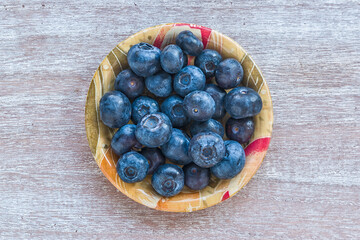 Blueberries in a bowl on wooden table. Top view