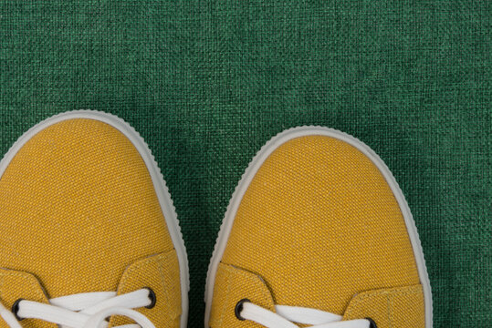 Top view of fashionable mustard-colored shoes. The shoes are on a green burlap. The shoe fabric is made from recycled textiles. Eco-friendly comfort. The concept of caring for the environment