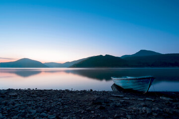 Old boat at rest on a placid lake in the blue hour before sunrise