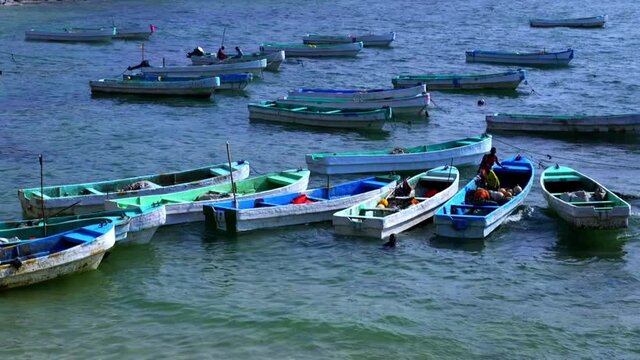 Several Locals Unloading Water On The Boats Floating On The Coast Of The Port Of Kismayo In Somalia As They Prepare For An Adventure On The Somali Sea During Daytime.