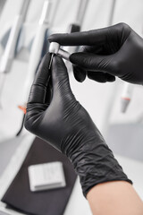 Macro snapshot of dentist's hands in black gloves holding drill head. Dentist office. Instruments and orthodontic tools. Vertical closeup snapshot