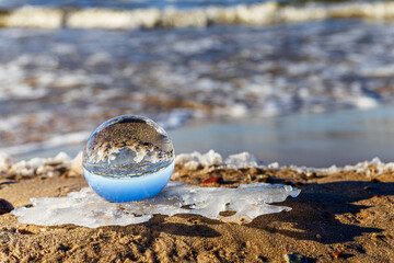 Fototapeta na wymiar Glass ball stands at sea in the sand of Jurmala