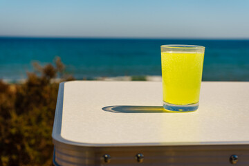 Citrus drink in glass on sea shore