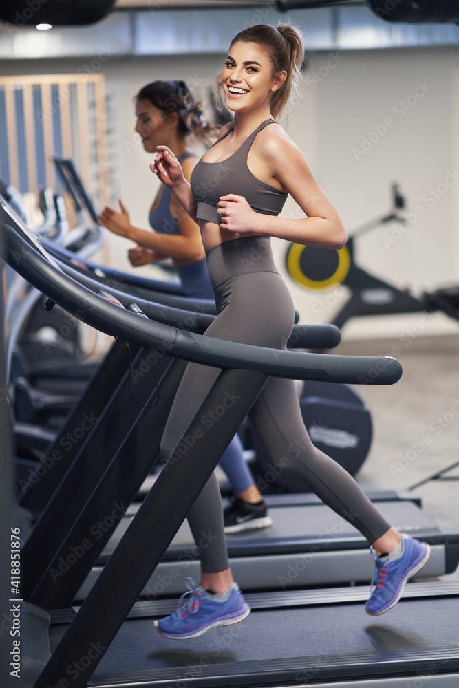 Wall mural Two girl friends working out on treadmill