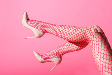 Female legs raised in sexy pink fishnets and high heels - obrazy, fototapety, plakaty